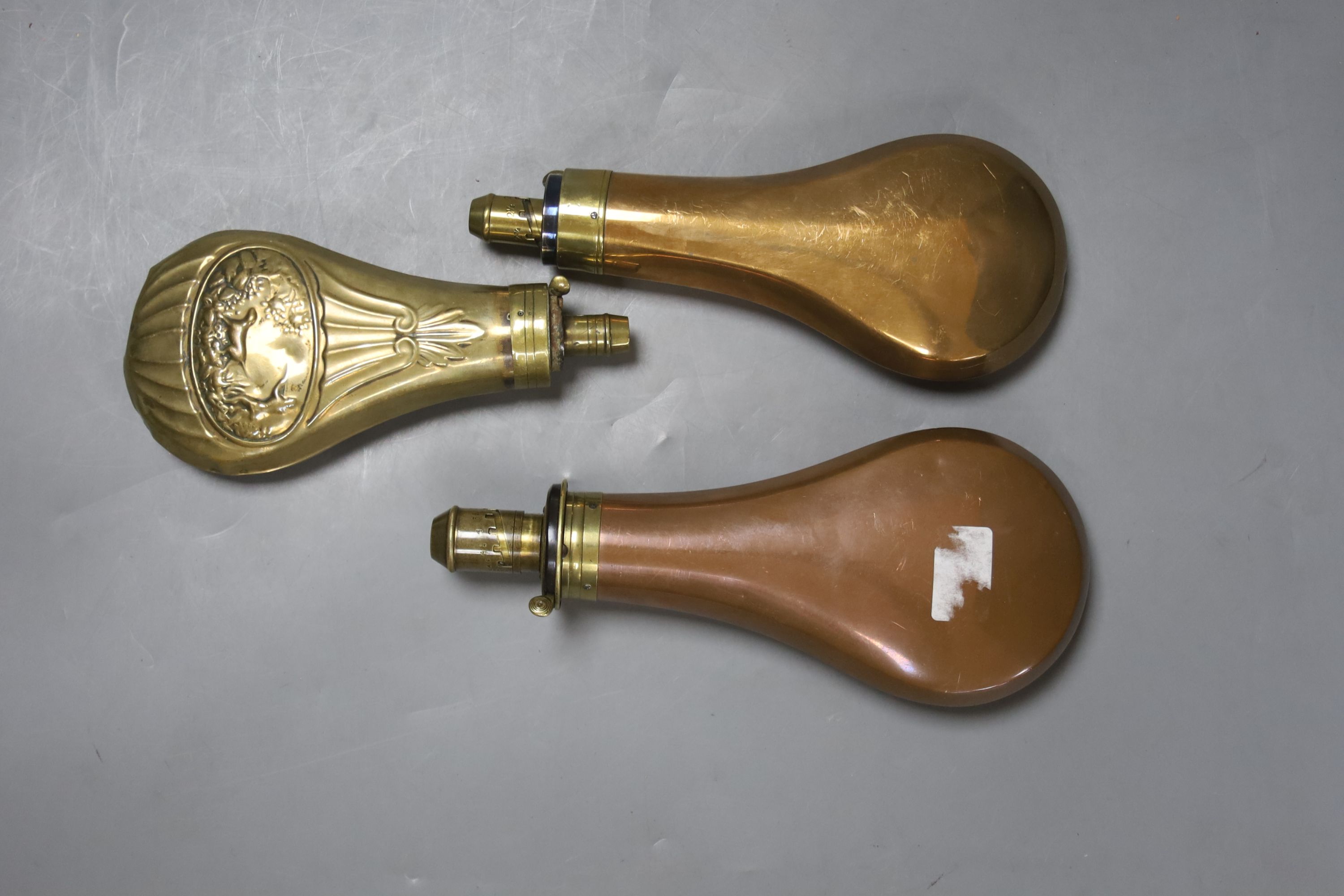 An 19th century embossed brass powder flask and two copper powder flasks, one with 4 drams capacity